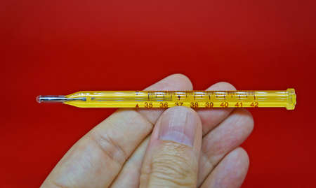 Rio de Janeiro, Brazil - January 23, 2021: Hand holding a mercury thermometer for body temperature.