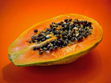 Half a papaya on orange background