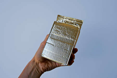 Ground coffee vacuum packaging in golden foil on hand