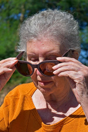 Elderly woman putting on sunglassesの写真素材