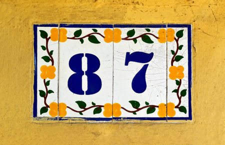 Street sign number 87 on a yellow wall
