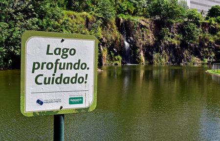 RIBEIRAO PRETO, SAO PAULO, BRAZIL - April 19, 2023: Warning sign in Portuguese informing "Deep lake, be careful"のeditorial素材
