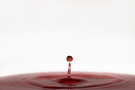 drops of wine falling into glassの写真素材