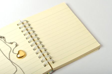 A golden heart necklace on a empty page of diary の写真素材