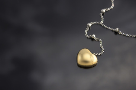 Golden heart with necklace chain on black   の写真素材