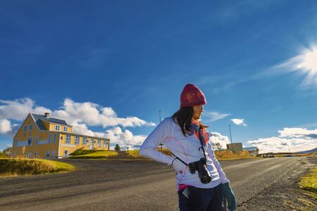 A traveler woman walking on the street for sightseeing the typical Icelandic landscape with houses and beautiful blue sky background, Icelandの写真素材