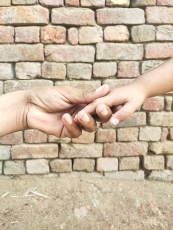 Mother and daughter holding hands on brick wall background, family love conceptの写真素材
