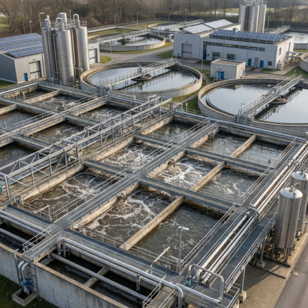 High-angle aerial view of a modern wastewater treatment plant. Bubbling aeration tanks and circular clarifiers showcase the purification process, powered partly by rooftop solar panels.の素材