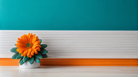 A single orange flower in a white pot against a teal and white wall.の素材