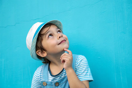 A cute girl in a yellow beret thoughtfully looks up against yellow background.の素材