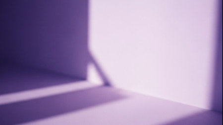 Vibrant purple and lavender shadows create an abstract pattern on a plain wallの素材