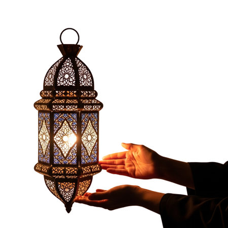 Hands gently cradle a detailed Moroccan lantern illuminated from within, creating a warm glow against a black backgroundの素材