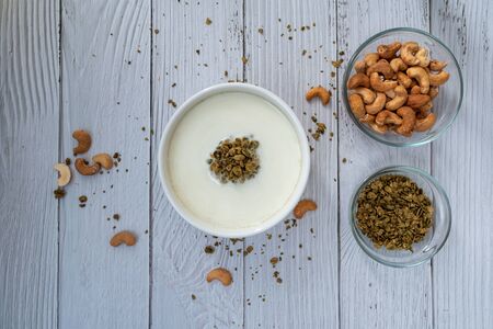 Bowl of cereal matcha oat granola with oat milk, cashew nuts on white wood  Background. vegan foodの写真素材