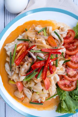Stir-fried squid with salted egg yolk, onion, spring onion and Chili pepper on white plate. Food concept. Thailand seafood cuisine. thai foodの写真素材