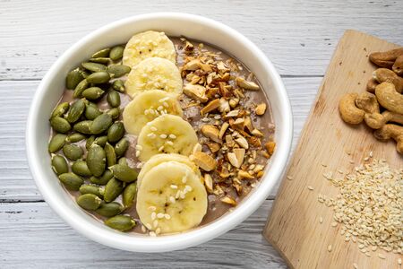 Chocolate smoothie bowl (Chocolate , avocado , banana , almond milk) topped with sliced banana, Pumpkin seeds, chopped  nuts and sesame seeds.の写真素材