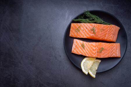 Raw salmon filet with rosemary and lime on dark slate background, wild Atlantic fish. Delicious fish meat. top viewの写真素材
