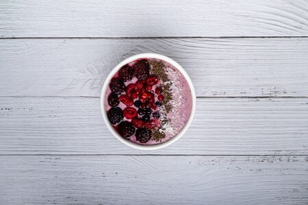 Healthy breakfast berry smoothie bowl topped with Blueberries, blackberries, chia seeds, raspberry and grounded coconut flakes. top view.Healthy food concept. copy spaceの写真素材