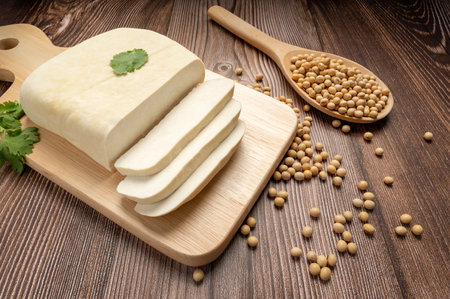 Fresh tofu and sliced Tofu on wood cutting board with soy bean in wooden spoon. full depth of field....