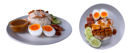 Barbecued red pork, crispy pork belly, boiled egg with rice and red sauce served with cucumber slices.の写真素材
