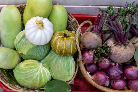 Colorful assortment of fresh vegetables and fruits displayed in woven baskets at a local market in autumnの写真素材