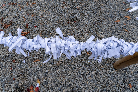 Strands of shredded paper hang on a line above a ground covered with small stones. The scene shows a simple outdoor setup with no people around.の写真素材