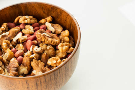 Mixed nuts in a wooden bowl on a white backgroundの写真素材