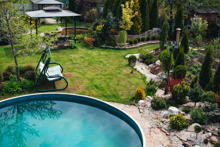 Country garden with a round pool, swings and plants. Private courtyard.