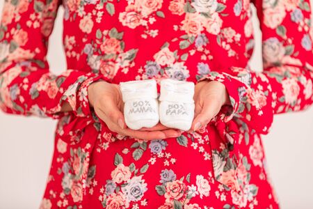 Young pregnant woman holding baby booties - Gender reveal