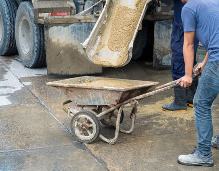 Controlled Low Strength Material (CLSM) pouring down from mixer truck to a trolley and workers still workingの写真素材