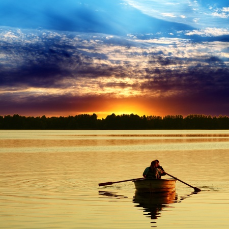 Couple in boat against a beautiful sunsetの写真素材