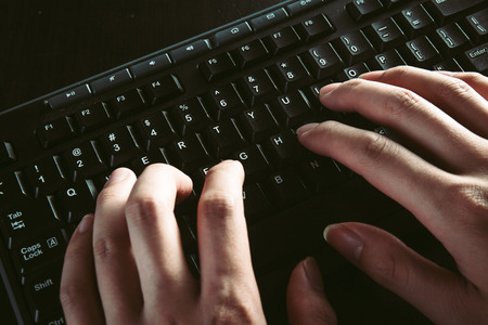 Close up view of hands typing on a keyboard