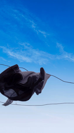Silhouette of a man's face mask on the wire against the blue sky