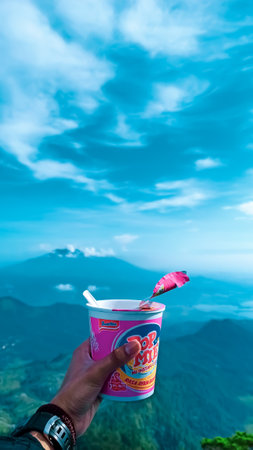 Unidentified man hand holding instant coffee cup with blue sky background.の写真素材