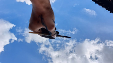 Hand of a man with a knife in his hand against the skyの写真素材