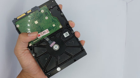 Hand holding hard disk drive on white background. Close up view.