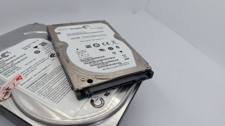 Old hard disk drive on white background, closeup of photo.