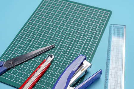 Scissors, cutter knife and stapler on cutting mat