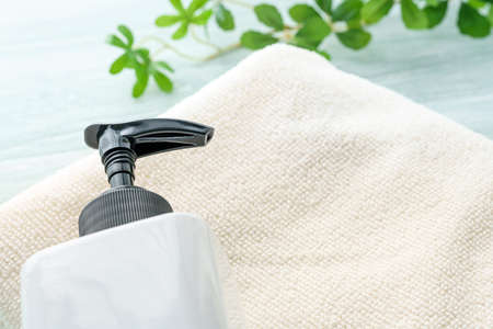 Liquid soap bottle and towel on wooden background