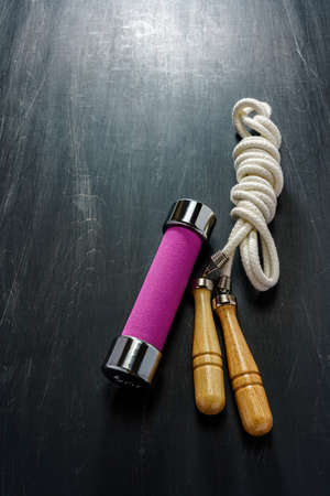 Fitness equity (drumbell, skip/jump rope) on wooden backgroundの写真素材