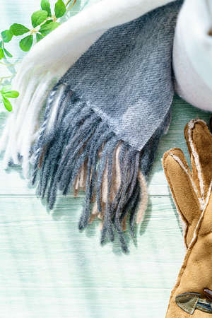 Woolen scarf and gloves on wooden backgroundの写真素材
