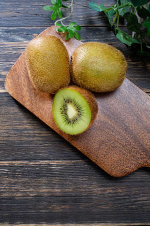 Kiwi fruits and cutting board on wooden tableの写真素材