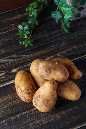 Raw unpeeled potatoes on wooden tableの写真素材