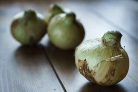 Raw unpeeled onions on wooden tableの写真素材