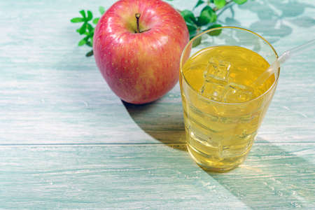 Fresh apple juice in glass isolated on wooden tableの写真素材