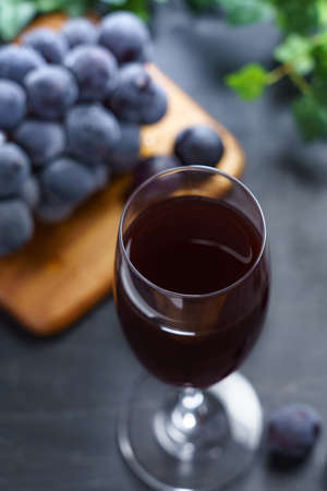 Fresh grape juice in glass on wooden table