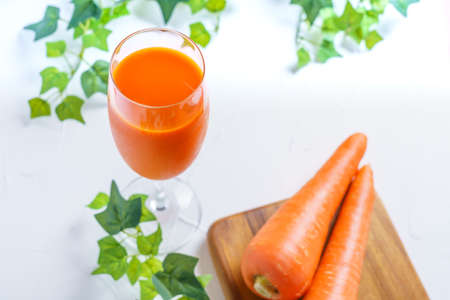 Carrot juice in glass isolated on wooden tableの写真素材