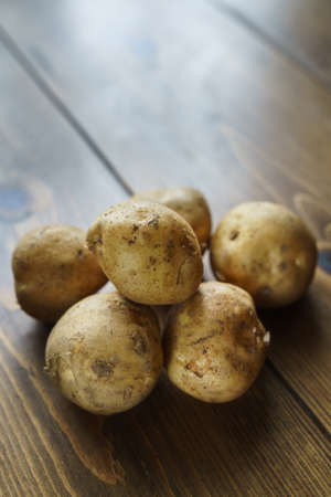 Raw unpeeled potatoes on wooden table