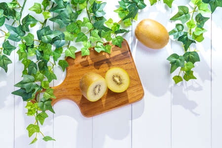 Kiwi fruits and cutting board on wooden tableの写真素材