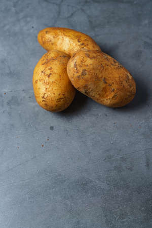 Raw unpeeled potatoes on wooden tableの写真素材