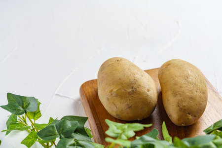 Raw unpeeled potatoes on wooden tableの写真素材
